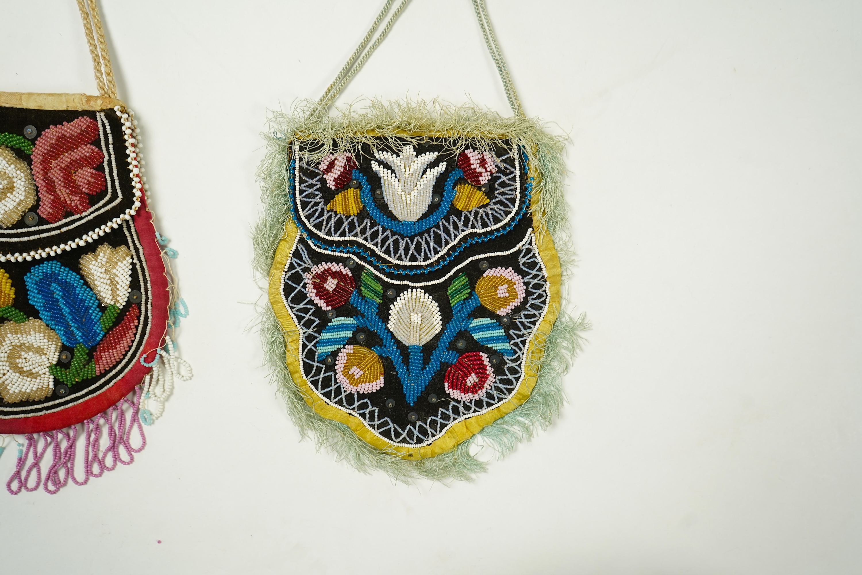 Two Native American Iroquois beaded bags. One edged with fine pale blue silk fringing, the other larger with bead worked fringing. Largest 16.5cm high. Condition - The blue fringed bag has a few sequins missing and the f